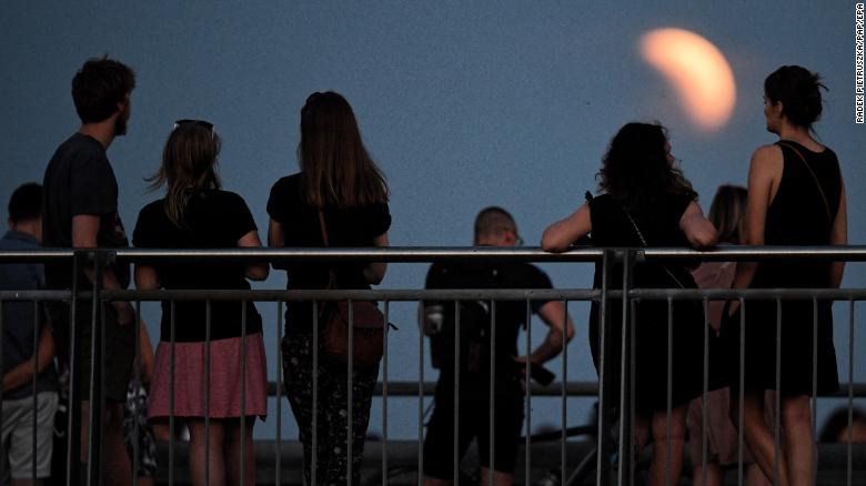 epa06914587 People watch the lunar eclipse in its beginning phase in Warsaw, Poland, 27 July 2018. The lunar eclipse on the night of 27 July 2018 is the longest total lunar eclipse of the 21st century with the event spanning for over four hours, and the total eclipse phase lasting for 103 minutes.  EPA/Radek Pietruszka POLAND OUT